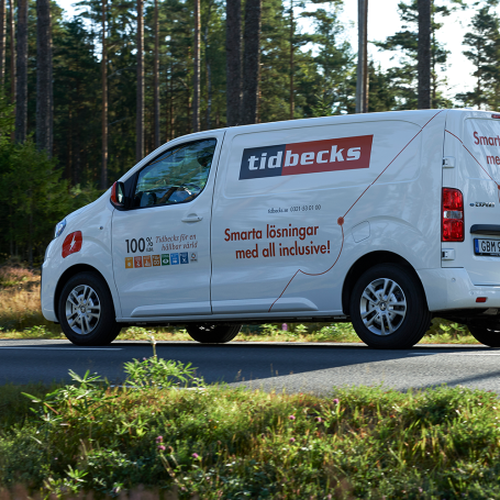 Skåpbil med tidbecks logotyp kör på väg i skogen