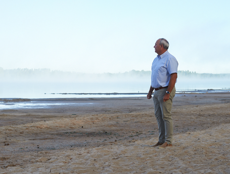 VD Sven-Olov står på en strand och blickar ut mot sjön