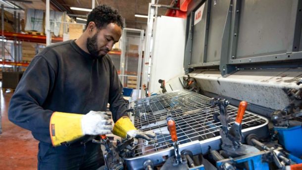 En medarbetare spänner fast ett galler i en maskin