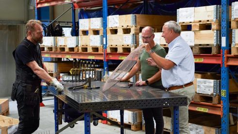 Personer i teamet står vid ett bord och diskuterar ett gallerskydd som tillverkats