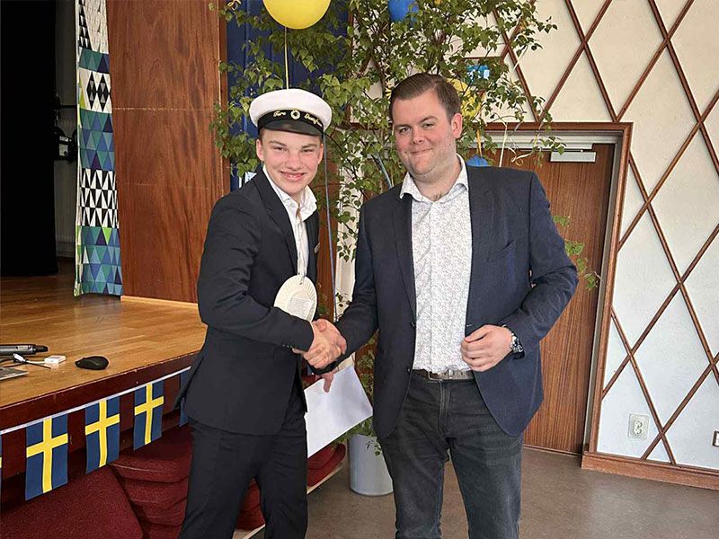 Två personer tittar mot kameran och skakar hand under ett studentfirande.