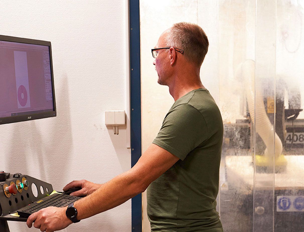 En medarbetare står och arbetar vid en dator 
