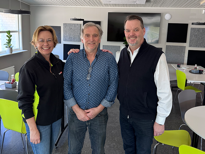 Tre anställda står och ler mot kameran