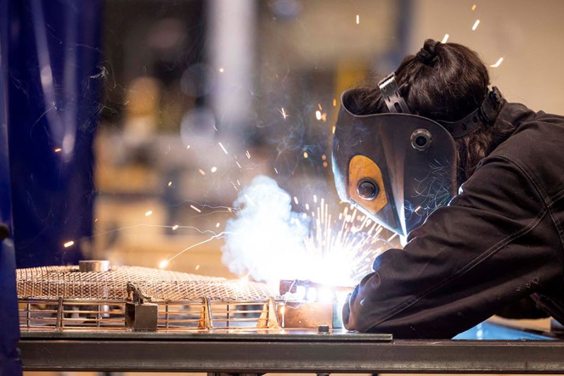 Personal som svetsar fläktskydd i produktion