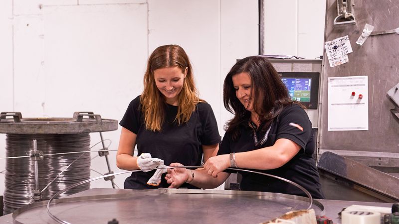 Två medarbetare kontrollerar en metalltråd