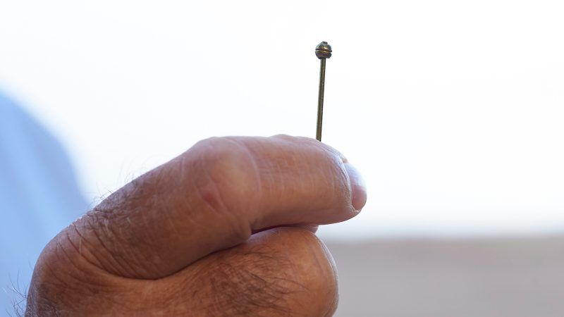 Hand håller upp en knappnål