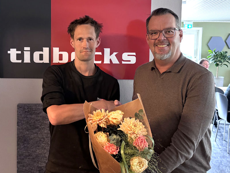 Två personer tittar mot kameran med en blomsterbukett i handen