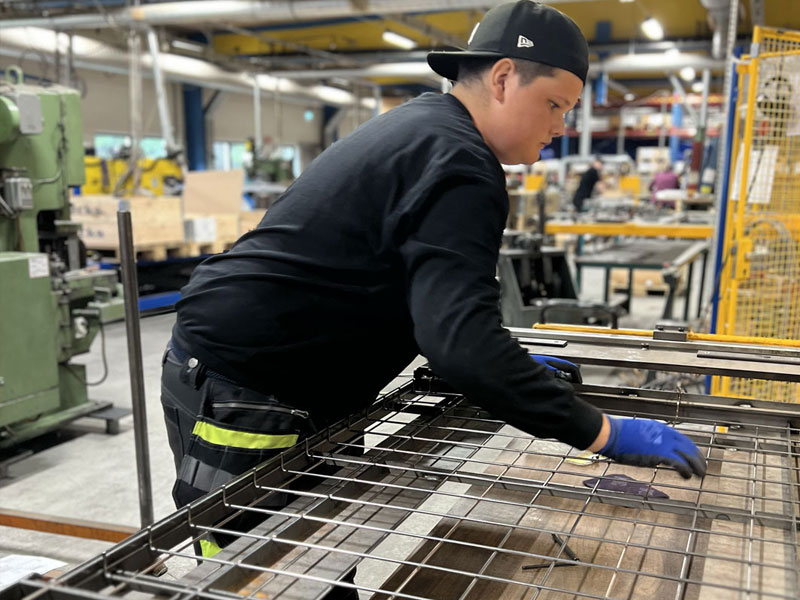 APL praktikant står och arbetar vid maskin